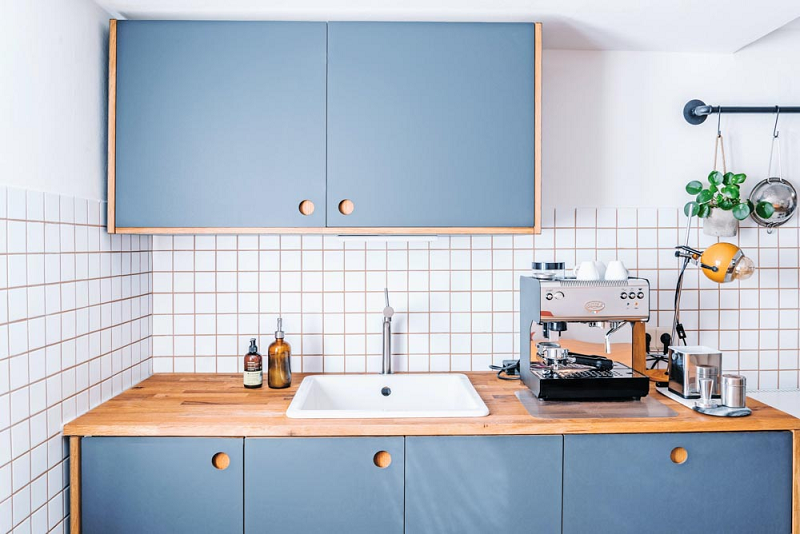 Tủ bếp giá rẻ tone màu xanh xám nhạt kết hợp với mặt bếp gỗ tạo điểm nhấn đầy ấn tượng.