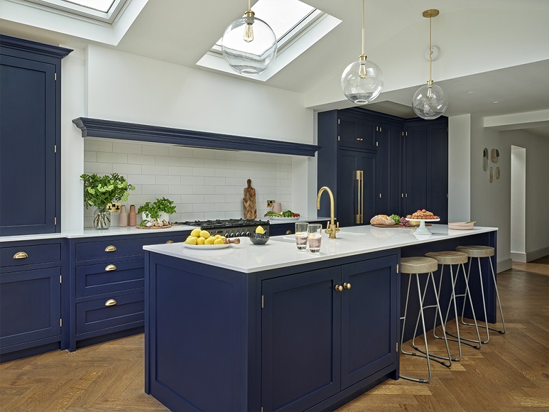 Mặt bàn bằng đá cẩm thạch và backsplash, phần cứng bằng vàng, núm tay cầm tinh thể cùng tủ bếp màu xanh làm cho một nhà bếp sang trọng