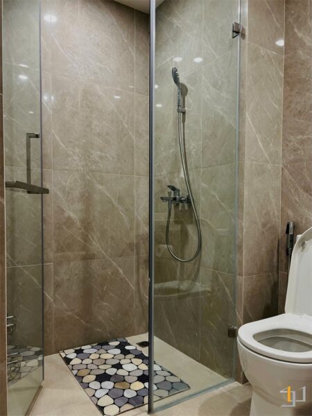 Phòng tắm được thiết kế hiện đại với vách kính cường lực trong suốt, ngăn cách khu vực tắm đứng và khu vực vệ sinh