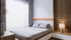 Giường ngủ có đầu giường bọc nệm đơn giản được đặt giữa mảng tường màu đất và vách ốp sọc đứng